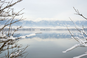 Mountain lake in winter with reflection of rocky mountains on surface
