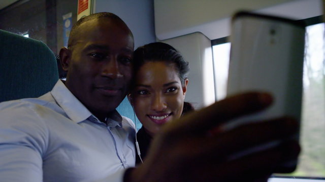 Attractive couple on train journey pose for selfie with camera phone.