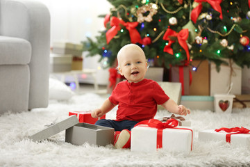 Obraz na płótnie Canvas Funny baby with gift boxes and Christmas tree on background