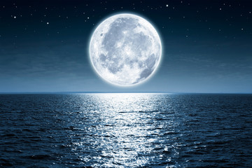 Volle maan stijgt & 39 s nachts boven de lege oceaan met kopieerruimte