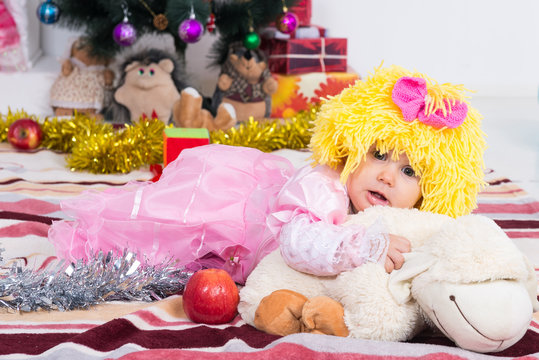 Little girl in a wig is on a pillow in the New Year