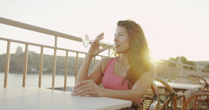  Portrait of beautiful woman drinking wine outdoors as the sun begins to set. 