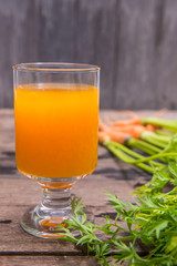 Fresh-squeezed carrot juice on wooden background