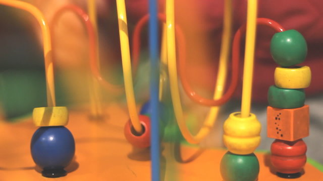 Children hand playing colorful bead roller coaster