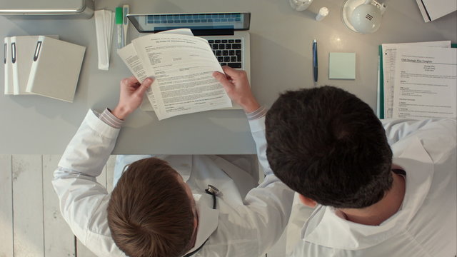Doctor signing a medical report in his office. Top view