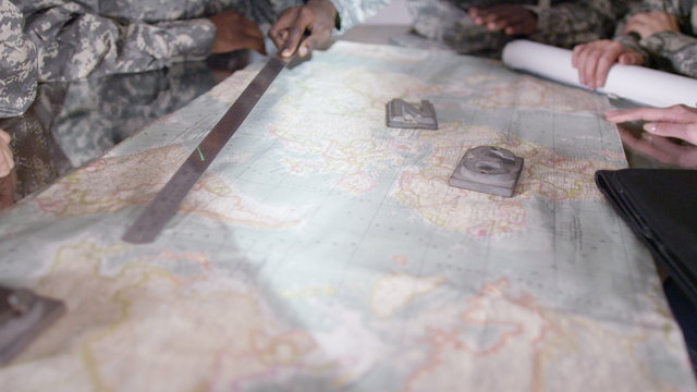  Female military officers in army office, looking at a map and discussing battle strategy. 