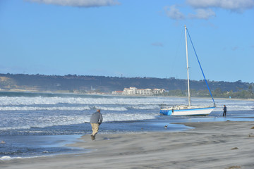 An Abandoned Yacht stranded on a beach in San Diego during rough weather, 
