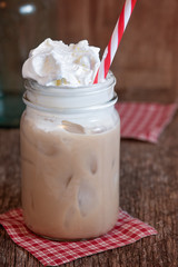 Iced coffee with whipped cream and a straw in a jar