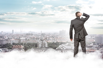 Man standing on clouds looking at city