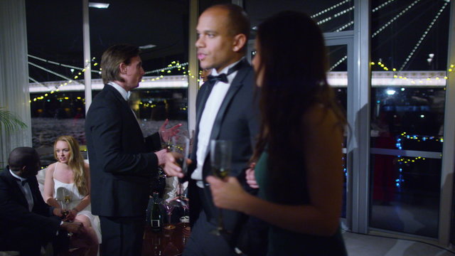  Attractive couple chatting at glamorous party, with city lights in background