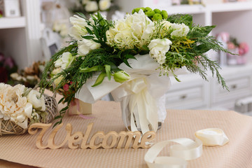 Stylish wedding cream flower bouquet near welcome sign