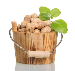 Unshelled peanuts in a wooden bucket closeup isolated on white b