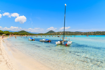 Catamaran boat on turquoise sea water of Santa Giulia beach, Corsica island, France