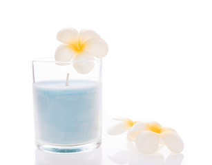 Obraz na płótnie Canvas A blue candle glass decorative with frangipani flowers on white
