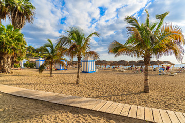A view of sandy El Duque beach with tropical palm trees in Costa Adeje town, Tenerife, Canary Islands, Spain