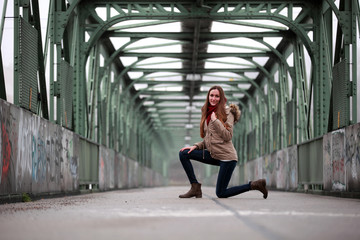 Beautiful brunette girl kneeling on a bridge
