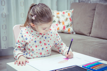 Little girl is painting and drawing with pencil.