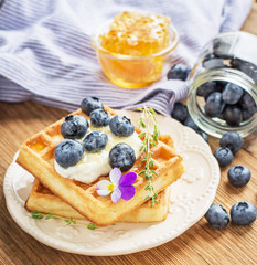 Belgian golden waffles for breakfast with fresh berries and flower honey on wooden background. The concept of home-cooked breakfast.