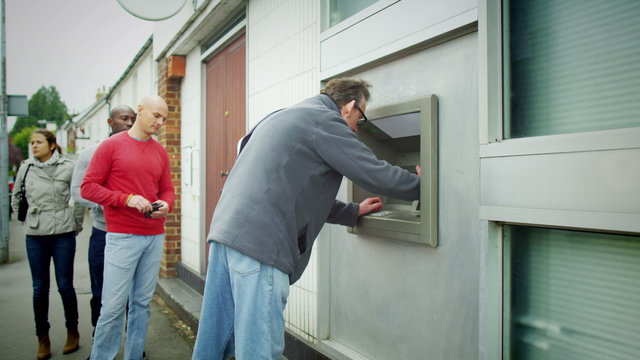People queuing to get cash from an ATM machine