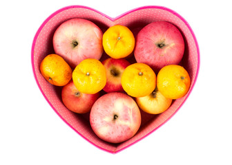 orange and apple mixed in heart-shaped gift box on white