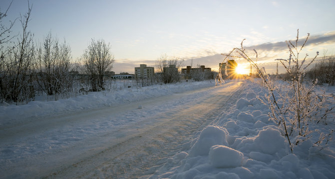 Winter road leading to the house at sunset.