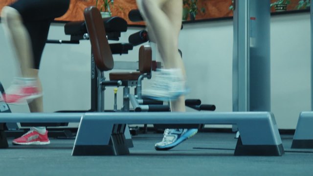 Aerobics class stepping together led by instructor at the gym