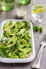Salad with savoy cabbage, avocado, cucumber and nuts on white pl