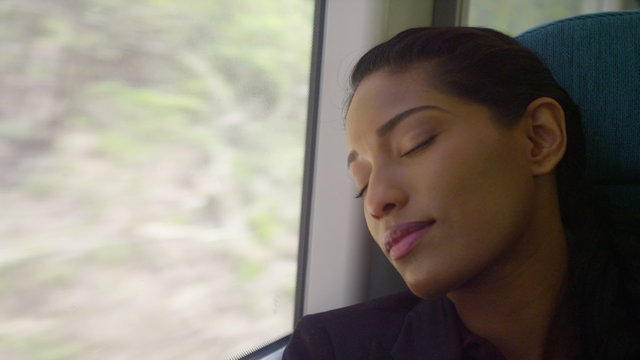  Beautiful woman looking out of window and falling asleep on train journey.