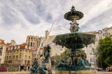 Fototapeta premium fountain in rossio square with cityscape of barrio quarter