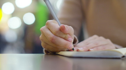Close-up of female hands writing in a diary