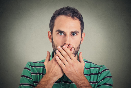 Closeup portrait man with hand over his mouth, speechless