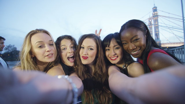  Attractive fun loving female friends pose to take a selfie at party