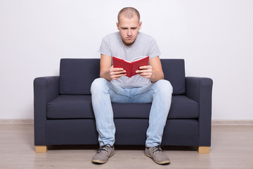 handsome man sitting on sofa and reading book