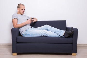 handsome man sitting on sofa and using smart phone