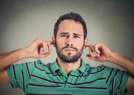 headshot displeased man plugging ears with fingers doesn't want to listen