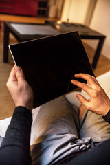 Modern middle-aged man with glasses enjoying a quiet moment comfortably at his home with a tablet