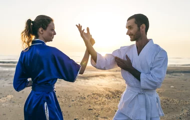 Abwaschbare Fototapete Kampfkunst Couple training martial arts on the beach