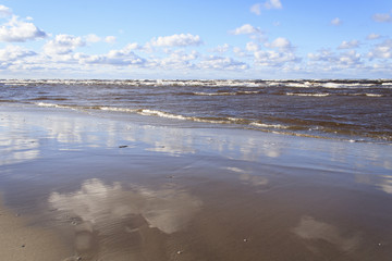 Clouds over the Baltic sea, the beach, the waves, the reflection.