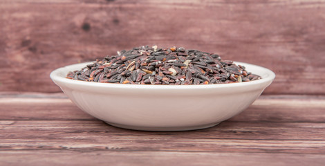 Black glutinous rice in wooden bowl over wooden backgound