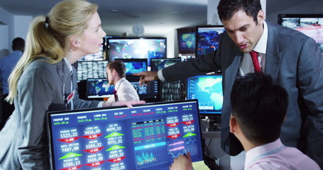 Team of financial brokers watching the world markets in a busy trading room