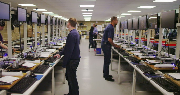 Timelapse of busy team of workers testing computers in electronics factory
