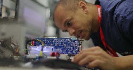 Male worker in an electronics factory working on computer testing and repairs