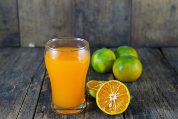 Orange juice in glass , fresh fruits on wooden background 