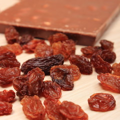 Nutritious chocolate with nuts and raisins on wooden table
