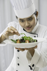close up of female chef patiently placing salad on a plate
