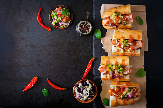 Hot dog - sandwich with Mexican salsa on dark background. Top view