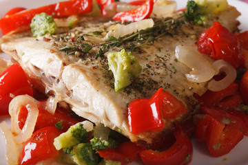 Baked flatfish with vegetables macro on a white plate. horizontal

