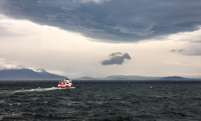 Obraz premium Boat on a choppy sea with Icelandic mountains behind.