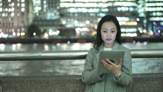 Attractive professional Asian woman using computer tablet in the city at night