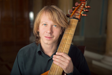 handsome  young musician play viola da gamba in palace